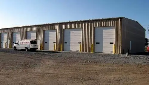 A row of steel garage bays with an L & M Electric van parked at the end